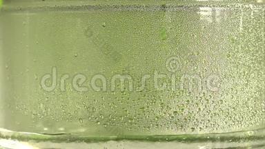 纯净水或酒精滴在玻璃罐内，绿色背景。 蒸馏过程。 特写